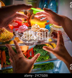 Menschliche Hände für süße Kuchen nachts in den offenen Kühlschrank Stockfoto