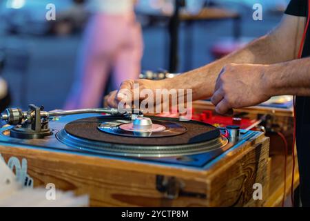 Nahaufnahme von DJ-Hands-on-Vinyl-Plattenspieler mit Holzkoffer. Professionelle Musikgeräte in Aktion. Analoge Oldtimer-Audio-Einrichtung auf Partys oder Clubveranstaltungen. Stockfoto