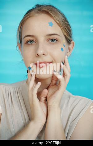 Porträt einer lächelnden Frau mit Sternenaufklebern im Gesicht Stockfoto