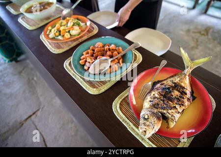 Ein köstlicher Teller mit traditionellem indonesischem gegrilltem Fisch, serviert mit lokalen Beilagen und Sambal, zeigt authentische Küche in Sulawesi. Stockfoto
