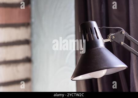 Dieses Bild zeigt die Nahaufnahme einer eleganten schwarzen Lampe mit einem eleganten weißen Schirm, der auf dem Sockel montiert ist Stockfoto