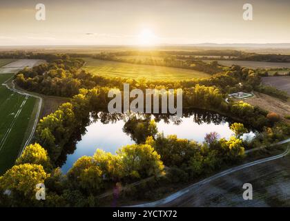 See im ländlichen Raum bei Sonnenuntergang, Drohnenblick. Ländliche Landschaft mit Seen. Teich auf dem Land mit Feldern. Grünes Farmfeld und Ackerland auf dem Land. Dorf in Stockfoto
