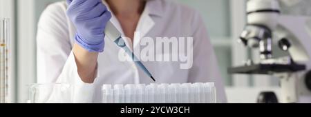 Der Chemiker tropft das Reagenz mit der Pipette in die Reagenzgläser Stockfoto