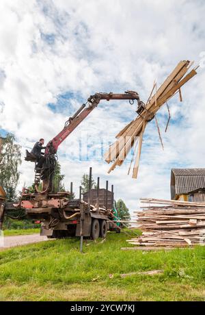 Baumstamm-hydraulischer Manipulator entlädt am Sommertag Holz vom Lkw Stockfoto