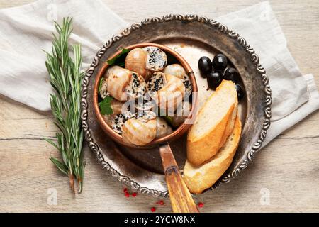 Teller mit gebackenen Schnecken gefüllt mit Knoblauchbutter auf hellem Hintergrund. Draufsicht. Stockfoto