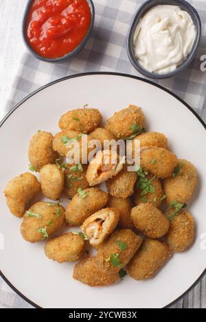 Panierte Muscheln, serviert mit Mayonnaise und Ketchup in Nahaufnahme auf einem Teller auf einem Tisch. Vertikale Draufsicht von oben Stockfoto