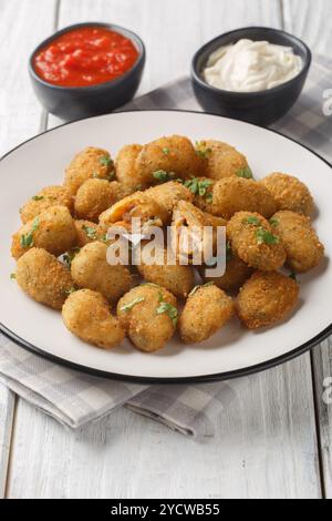 Vorspeise gebratene panierte Muscheln, serviert mit Mayonnaise und Ketchup in Nahaufnahme auf einem Teller auf dem Tisch. Vertikal Stockfoto