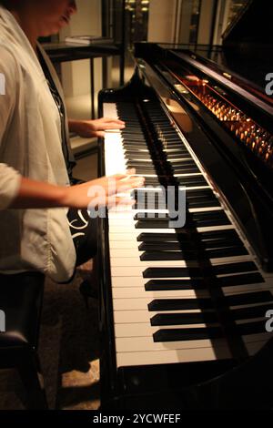 Kuala Lumpur, Malaysia - 26. November 2018: Nahaufnahme einer Frauenhände, die ein schwarzes, elegantes Klavier von Yamaha spielt. Stockfoto