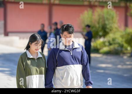 Ein koreanisches Paar, ein Mann in den 30ern und eine Frau in den 20ern, geht harmonisch durch ein historisches Gebäude in Seoul, Südkorea, mit Hanbok. Stockfoto