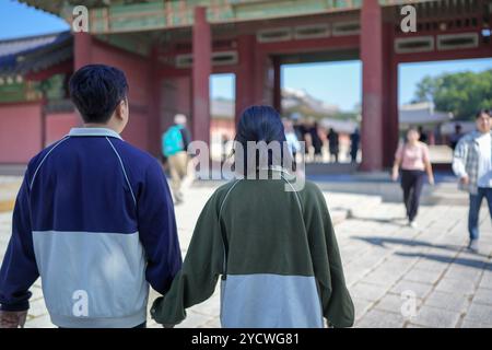 Ein koreanisches Paar, ein Mann in den 30ern und eine Frau in den 20ern, geht harmonisch durch ein historisches Gebäude in Seoul, Südkorea, mit Hanbok. Stockfoto