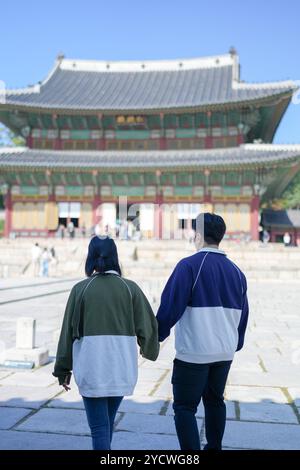 Ein koreanisches Paar, ein Mann in den 30ern und eine Frau in den 20ern, geht harmonisch durch ein historisches Gebäude in Seoul, Südkorea, mit Hanbok. Stockfoto