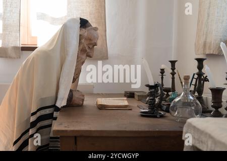 Wachsfigur eines alten weisen Juden, der einen Gebetschal oder Tallith trägt und an einem Tisch die Thora des heiligen jüdischen Textes studiert Stockfoto