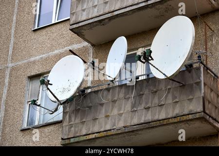 Satelliten-TV-Antennen auf Balkon für Kommunikation und Internet. Viele Antennen verblassten den Zustand an der Wand des Wohnhauses. Stockfoto