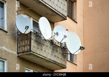 Satelliten-TV-Antennen auf Balkon für Kommunikation und Internet. Viele Antennen verblassten den Zustand an der Wand des Wohnhauses. Stockfoto