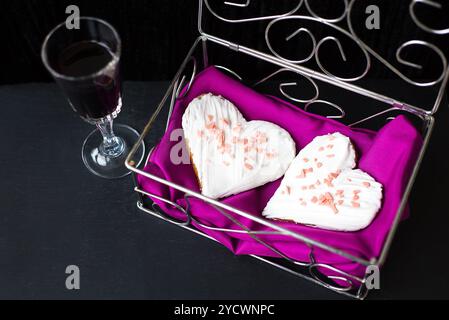 Glas Wein und Kekse in Form von Herzen liegt in einem Sarg Stockfoto