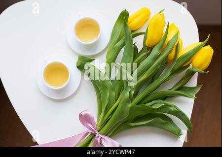 Schöne gelbe Tulpen, zwei Tassen grüner Tee, Frühling. Stockfoto