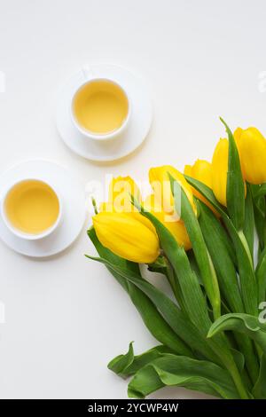 Schöne gelbe Tulpen, zwei Tassen grüner Tee, Frühling. Stockfoto