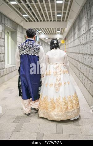 Ein Paar in traditioneller koreanischer Kleidung geht einen Tunnel hinunter. Der Mann trägt eine blaue Weste und die Frau ein weißes Kleid Stockfoto