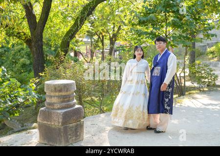 Ein koreanisches Paar, ein Mann in den 30ern und eine Frau in den 20ern, geht harmonisch durch ein historisches Gebäude in Seoul, Südkorea, mit Hanbok. Stockfoto