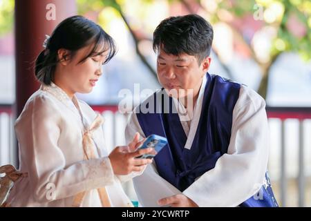 Ein koreanisches Paar, ein Mann in den 30ern und eine Frau in den 20ern, trägt glücklich Hanbok und sitzt in einem historischen Gebäude in Seoul, Südkorea. Stockfoto