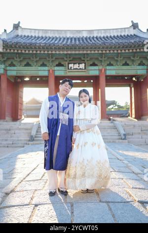 Ein koreanisches Paar in den 30ern und eine Frau in den 20ern stehen zusammen vor einem historischen Gebäude in Seoul, Südkorea, in Hanbok. Stockfoto