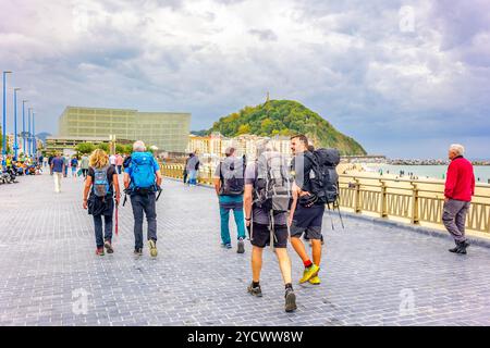 Eine Gruppe von Pilgern, die entlang des Zurriola-Strandes von San Sebastian / Donostia spazieren, eine wichtige Etappe auf der nördlichen Route des Jakobsweges. Stockfoto