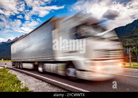 Lkw Rast auf der Autobahn im Hintergrund die Alpen. Lkw Auto in Bewegungsunschärfe. Stockfoto