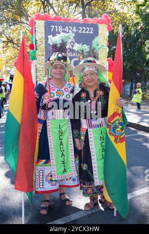 2 bolivianische Mitglieder von Incallajta Folk Dancers mit großen bolivianischen Flaggen vor der Bolivian Day Parade 2024 in Jackson Heights, Queens, New York. Stockfoto