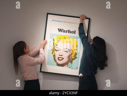 Mitglieder der Galerie positionieren ein signiertes Tate Gallery Poster von Andy Warhol, Marilyn Monroe, 1971, während eines Fotobesuchs in der neuen Galerie Shapero Modern in London, für ihre erste Ausstellung, The Modern Muse, mit berühmten Werken von Andy Warhol, David Hockney, Picasso, Grayson Perry und Banksy, die Kate Moss darstellen, mit den Haaren und dem charakteristischen Schönheitsfleck von Marilyn Monroe. Bilddatum: Donnerstag, 24. Oktober 2024. Stockfoto