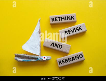 Überdenken Sie das Symbol „Überarbeiten“ und „Rebranding“. Holzblöcke mit Wörtern überdenken und neu gestalten. Schöner gelber Hintergrund mit Boot. Unternehmen und Umdenken Stockfoto