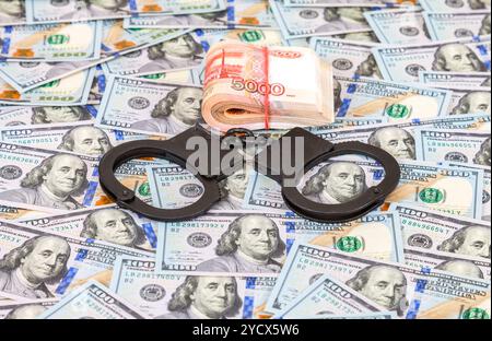 Stahl Polizei Handschellen liegen auf dem Hintergrund der amerikanische Dollar mit gefalteten Stapel von Banknoten der russische Rubel Stockfoto