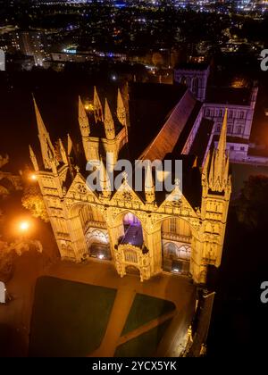 Peterborough Kathedrale glitzert Gold unter dem Nachthimmel, ihre beleuchtete Fassade und die Türme heben sich von der dunklen Stadt ab Stockfoto