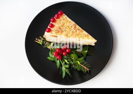 Ein Stück Kuchen, dekoriert mit Ästen und Beeren viburnum auf einem schwarzen Teller Stockfoto