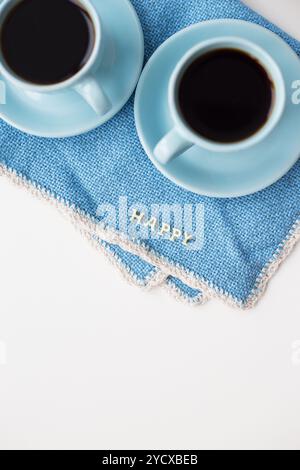 Zwei blaue Kaffeetassen auf blauer Serviette mit den Worten Happy Stockfoto