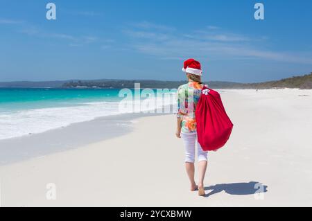 Weihnachten in Australien - Frau spaziert am Strand entlang mit festlichem weihnachtsmütze im Sommer Stockfoto