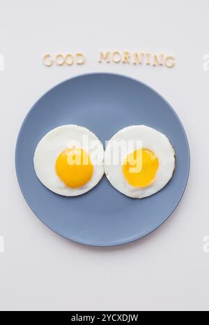 Zwei Eier auf einer Platte und einem gelben Serviette, Beschriftung Guten Morgen Stockfoto