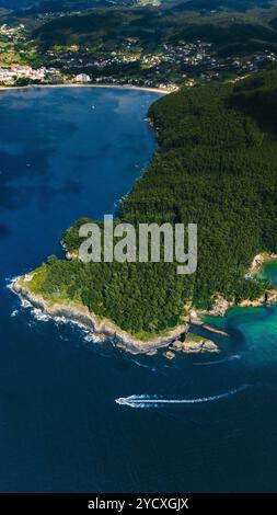 Atemberaubende Drohnenaufnahme, die die pulsierende Landschaft Galiciens mit einer grünen Halbinsel, azurblauem Wasser und einem malerischen Küstendorf einfängt Stockfoto