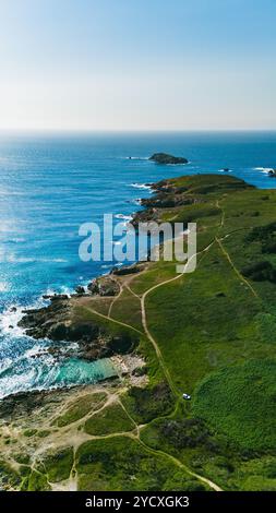 Luftaufnahme, die die atemberaubende Landschaft Galiciens mit lebendigem blauem Wasser, felsigen Ufern und Wanderwegen durch Hügel erfasst Stockfoto