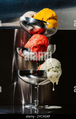 Eine verlockende Präsentation verschiedener Eiskugeln, darunter Aromen von Erdbeeren, Mango und Minzchips, die künstlerisch in einem eleganten Metallständer A serviert werden Stockfoto