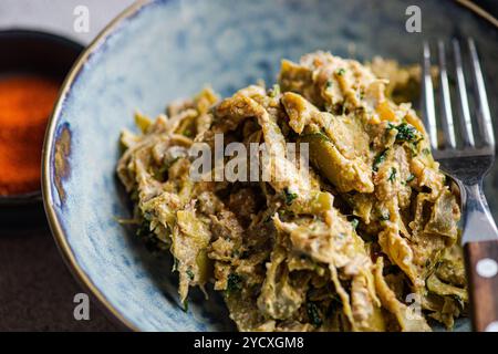 Ein köstliches georgianisches Gericht, Lobio, mit gedünsteten grünen Bohnen, gemischt mit Zwiebeln, scharfer Chili-Paprika und einer reichhaltigen Walnusspaste, serviert in einem rustikalen blu Stockfoto