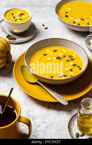 Rustikale Herbstkulisse mit cremiger Kürbissuppe mit Kürbiskernen und zerbröckeltem Fetakäse, mit Olivenöl getränkt, serviert in handgemachter Form Stockfoto