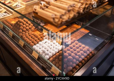Ein einladender Blick auf ein Schokoladengeschäft mit einer Auswahl an handwerklichen Pralinen, einschließlich staubter Trüffel und ordentlich gefütterten Schokoladentafeln unter Stockfoto