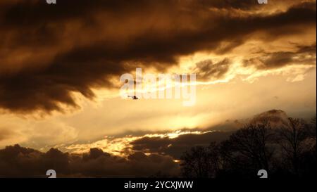 Eine ruhige Szene, die einen Hubschraubersilhouetten vor einem dramatischen, bewölkten Sonnenuntergangshimmel in Lausanne in der Schweiz feststellt und die Ruhe während der Reise darstellt. Stockfoto