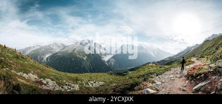 Wanderer auf einem Wanderweg bewundern den Panoramablick über die Schweizer und französische Grenze, mit üppigen Tälern und zerklüfteten Gipfeln unter einem weiten Himmel. Stockfoto