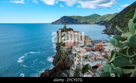 Lebhafte Häuser schmiegen sich an die Klippen von Cinque Terre und überblicken das türkisfarbene Wasser. Üppige grüne Hügel prägen dieses malerische Küstendorf Vernazza Italien Stockfoto