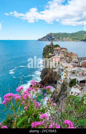 Erleben Sie die atemberaubende Küste von Cinque Terre, wo sich farbenfrohe Häuser an felsigen Klippen Klammern, während Wellen gegen die Küste krachen. Vernazza Italien Stockfoto