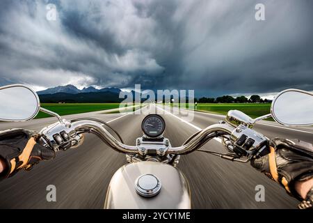 Biker auf einem Motorrad die Straße hinunter in ein Gewitter - Forggensee und Schwangau, Deutschland Bayern rast Stockfoto