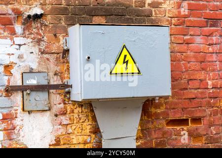 Altes gelbes Hochspannungs-Warnschild, das an der metallbox hängt Stockfoto