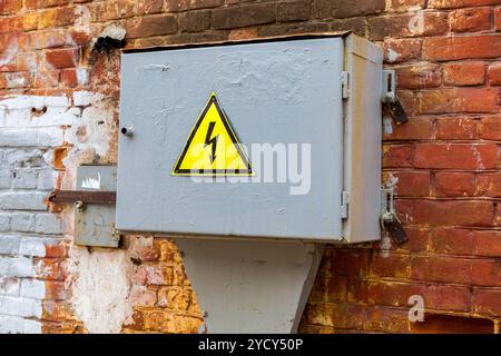 Altes gelbes Hochspannungs-Warnschild, das an der metallbox hängt Stockfoto
