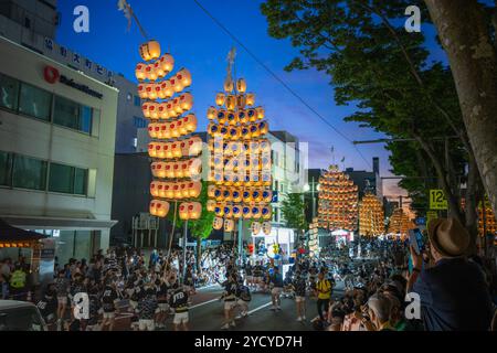 Akita, Japan – 5. August 2024: Eine Gruppe junger Menschen in traditionellen Trachten hält während des lebhaften Akita Kanto Festivals hohe gelbe Laternen. T Stockfoto